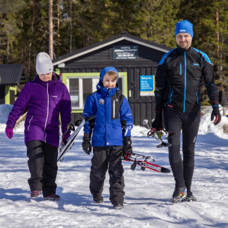 Pappa med två barn bär sina egna skidor och stavar med Fastgrip